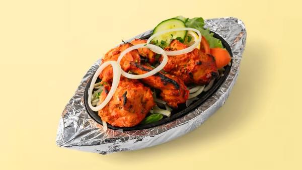 Poulet tandoori grillé servi avec des légumes.